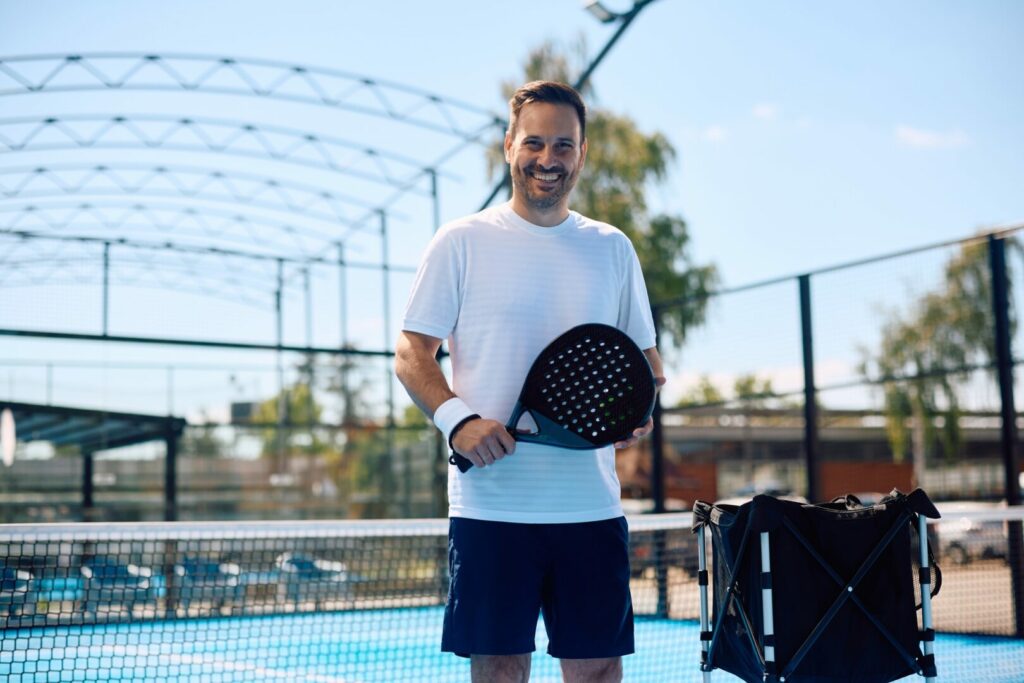 Happy athlete playing paddle tennis and looking at camera.