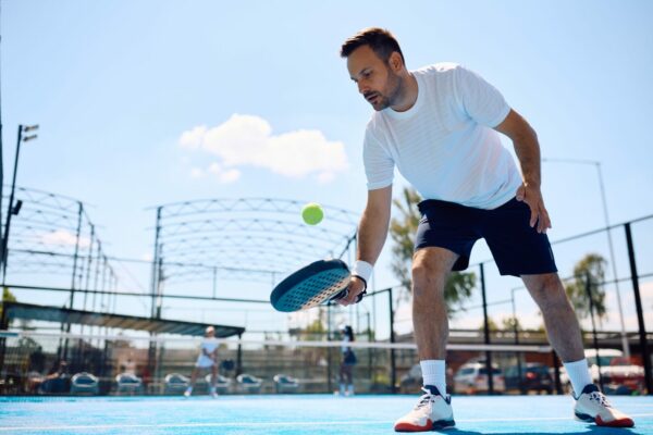 Paddle tennis player hitting the ball while playing match on the court.