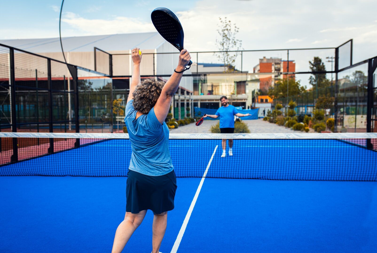 Rear view of female adult padel player celebrates victory in padel on outdoor court.