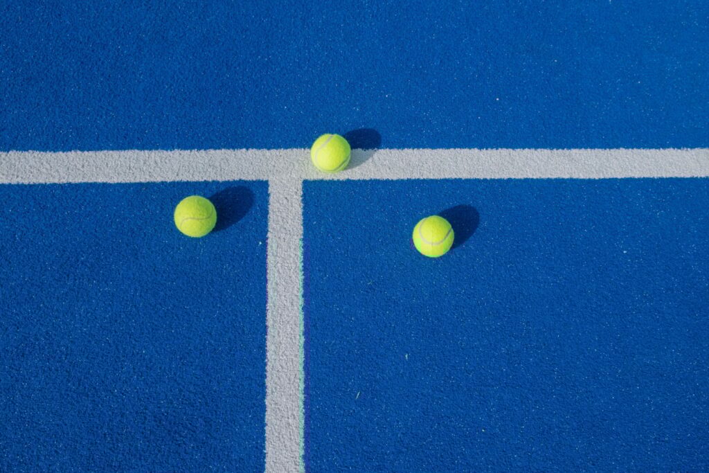 three padel tennis balls on a blue court